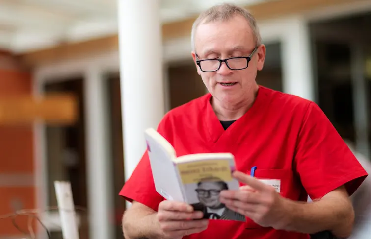 Glückliche Momente im Altenheim: Eine Betreuungskraft im Park von St. Vinzenz in Pfarrkirchen liest Bewohnern bei Sonnenschein Heimatgeschichten vor