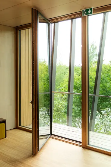 XXXL-Glasfront mit geöffneter Tür im Seminarraum der Hochschule im Hofgut Hafnerleiten. Barrierefreier Zugang und maximale Transparenz durch die Schreinerei Renaltner.