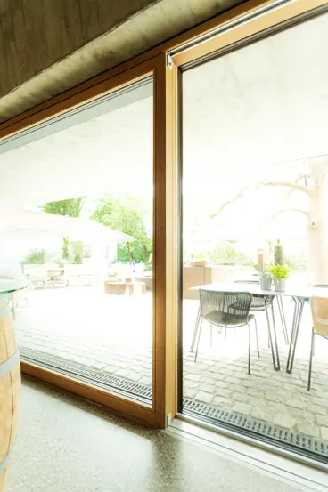 Geöffnete XXXL-Glasfront der Schreinerei Renaltner im Restaurant Hofgut Hafnerleiten. Barrierefreier Übergang durch weitläufige Panoramafenster und Hebe-Schiebe-Systeme.