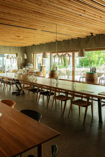 Innenansicht Restaurant Hofgut Hafnerleiten: Lichtdurchfluteter Gastraum mit XXL-Panoramafenstern und Blick auf die Natur, realisiert durch die Schreinerei Renaltner.