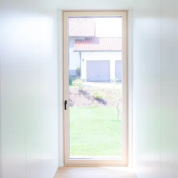 Bodentiefes Panoramafenster als Blickfang am Ende eines langen Gangs im Bungalow Fürstenzell. Gefertigt von der Schreinerei Renaltner (Passau), Ihr Partner für exklusiven Fensterbau in Niederbayern und München.