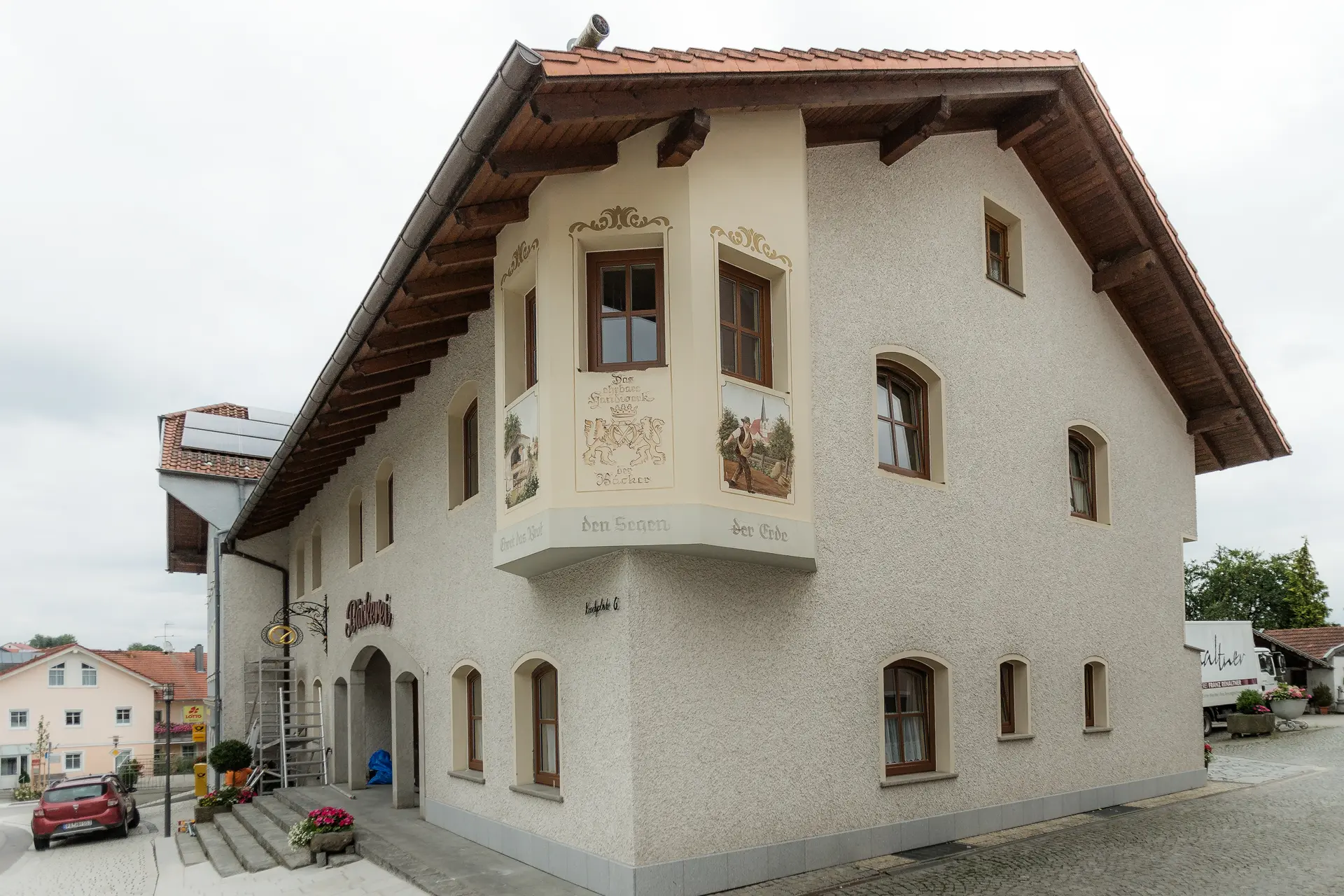 Maßgefertigte Holz-Alu-Fenster in spezieller Segmentform für eine Bäckerei in Neukirchen am Inn – farblich perfekt auf die Fassade abgestimmt durch Renaltner.