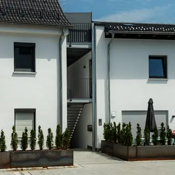 Blick vom Innenhof über den Parkplatz auf die Fassade der Wohnanlage in Neukirchen am Inn; verbaute Kunststofffenster der Schreinerei Franz Renaltner, Ihrem Spezialisten für Passau, Niederbayern, Oberösterreich und München seit 1926.