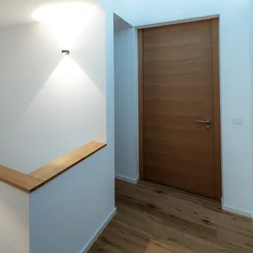 Blick durch einen lichtgefluteten Flur mit XXL Panoramafenster, Designtreppe und deckenhoher Innentür. Hochwertiger Innenausbau und Fensterbau durch die Schreinerei Renaltner (seit 1926)