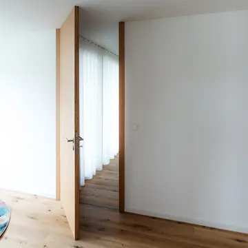 Raumhohe Innentür im Obergeschoss eines Wohnhauses in Passau. Geöffneter Durchgang in einem hellen Flur, gefertigt in höchster Schreinerqualität von der Schreinerei Renaltner – Spezialist für exklusiven Innenausbau seit 1926