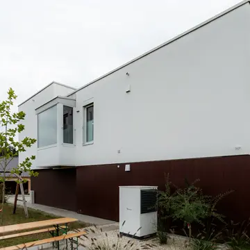 Seitenansicht eines Wohnhauses in Passau: Gartenbereich mit Wärmepumpe und maßgefertigten Fensterfronten von der Schreinerei Renaltner – Spezialist für Fensterbau in Niederbayern und Oberösterreich seit 1926.