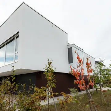 Außenansicht eines Wohnhauses in Passau mit Garage, Garten und Wärmepumpe. Die Fensterlösungen und der Eingangsbereich wurden von der Schreinerei Renaltner (Spezialist seit 1926) passgenau für den Neubau gefertigt.