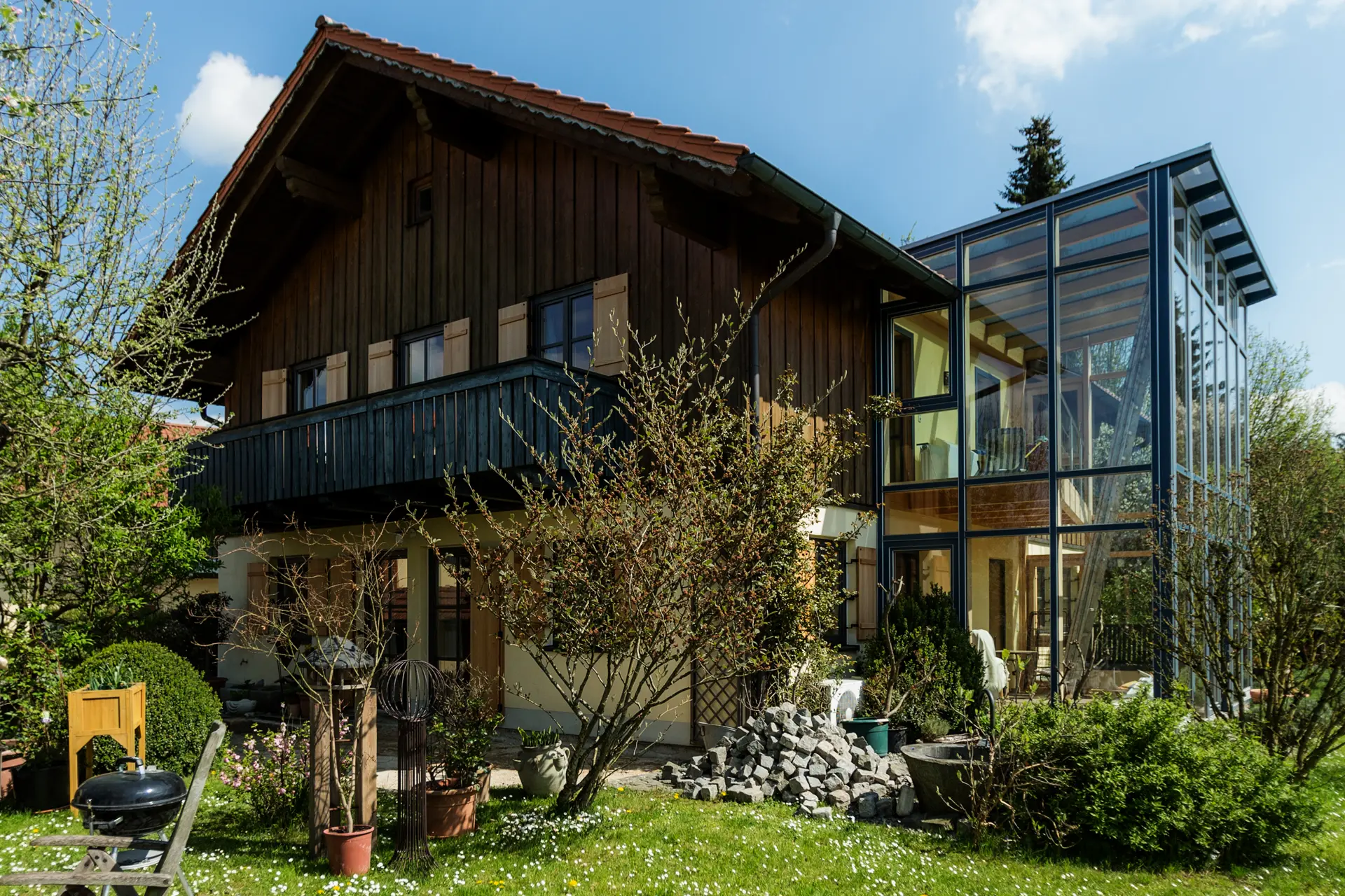 Gelungene Fenstersanierung in Passau: Kombination aus wetterfesten Holz-Alu-Fenstern und klassischen Holz-Fensterläden vor einer edlen Lärchen-Fassade von Renaltner.